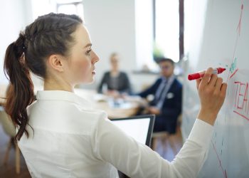 Young speaker with red highlighter explaining her vision of teamwork on whiteboard